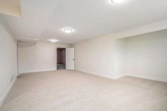 unfurnished room featuring baseboards, light colored carpet, and visible vents