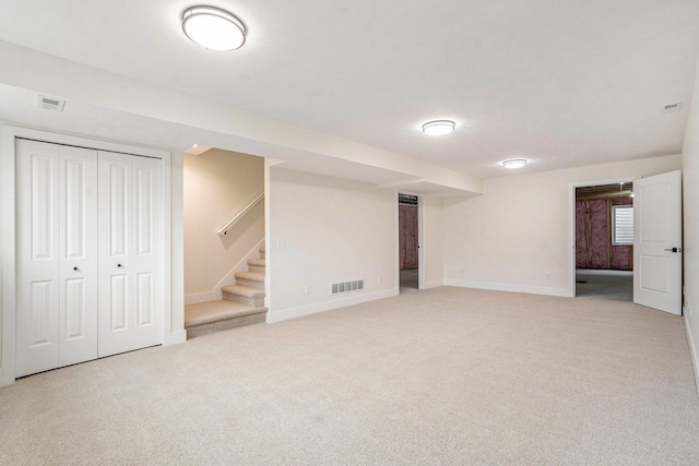 below grade area featuring stairs, visible vents, light colored carpet, and baseboards