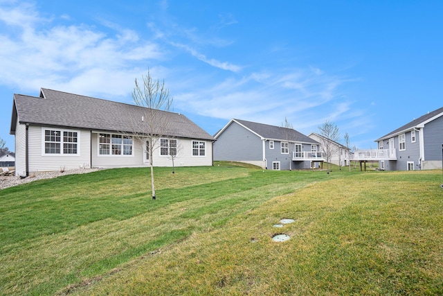 rear view of property featuring a shingled roof and a yard