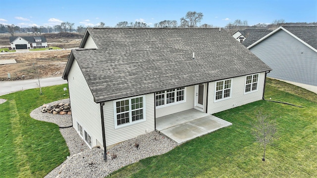 view of front facade with a front yard, a shingled roof, and a patio