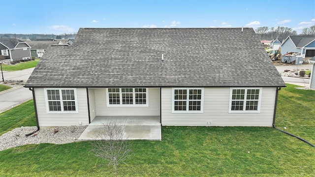 back of house with roof with shingles, a patio, and a yard