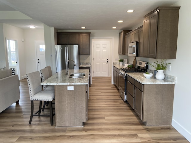 kitchen with a breakfast bar area, a sink, dark brown cabinets, and appliances with stainless steel finishes