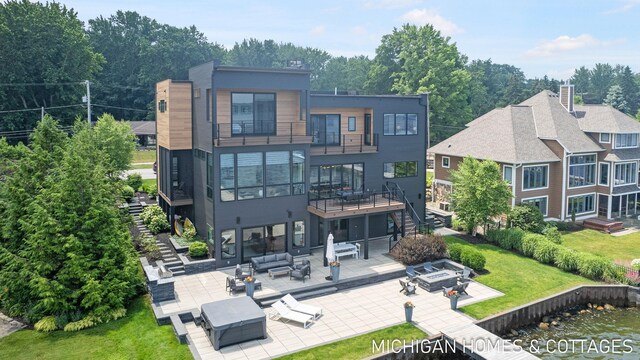 back of property featuring a balcony, an outdoor hangout area, a patio, and a yard