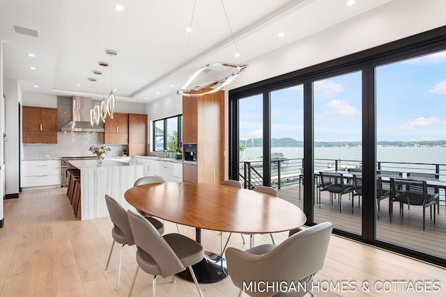 dining area with a water view and light hardwood / wood-style floors