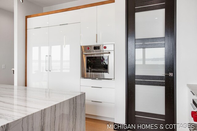 kitchen featuring white cabinets, french doors, oven, and light stone countertops