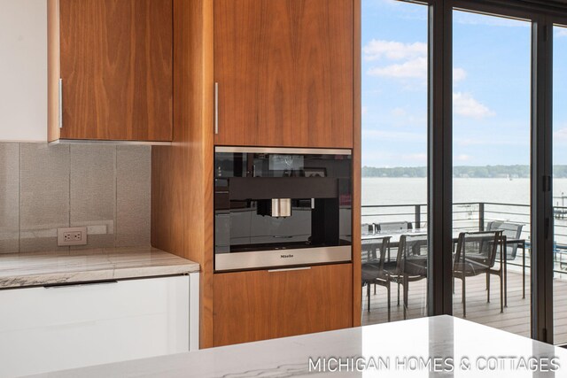 kitchen with oven, a healthy amount of sunlight, a water view, and tasteful backsplash