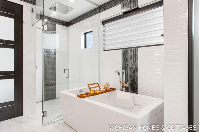 bathroom featuring shower with separate bathtub and tile walls