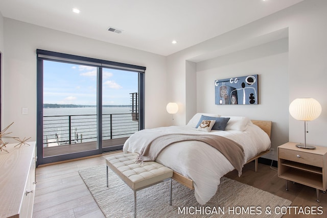 bedroom featuring access to outside, a water view, and light hardwood / wood-style floors