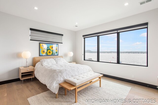 bedroom featuring a water view and light wood-type flooring