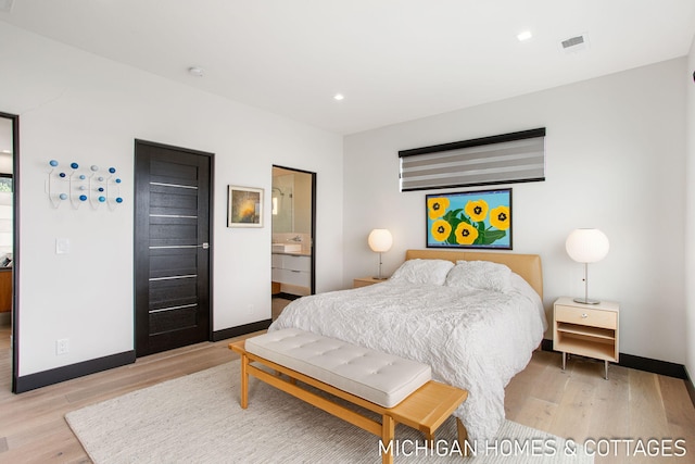 bedroom with ensuite bathroom and light hardwood / wood-style flooring