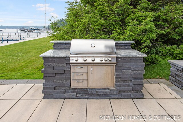 view of patio featuring area for grilling, a water view, and exterior kitchen