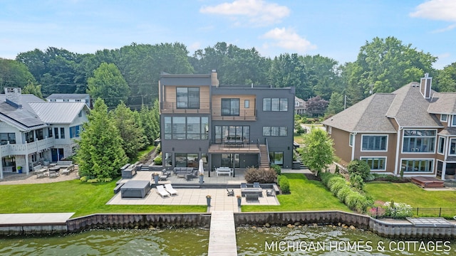 back of property with a lawn, a water view, and a patio