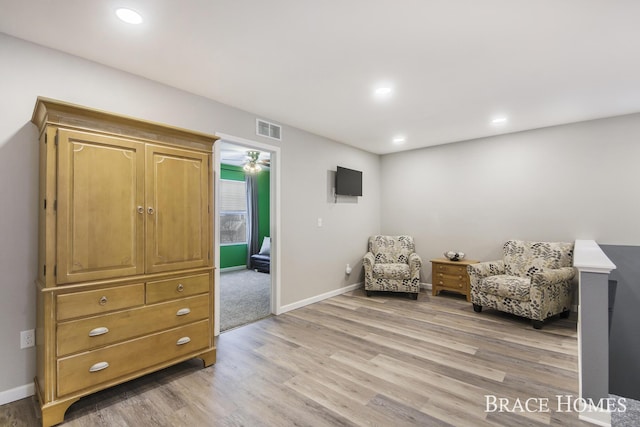 living area featuring light wood-type flooring and ceiling fan