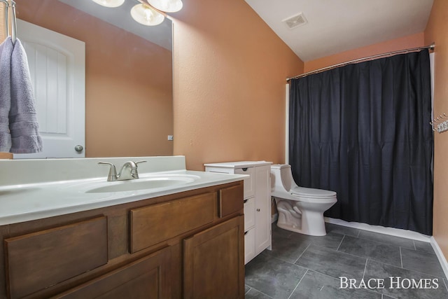 bathroom featuring vanity, toilet, and vaulted ceiling