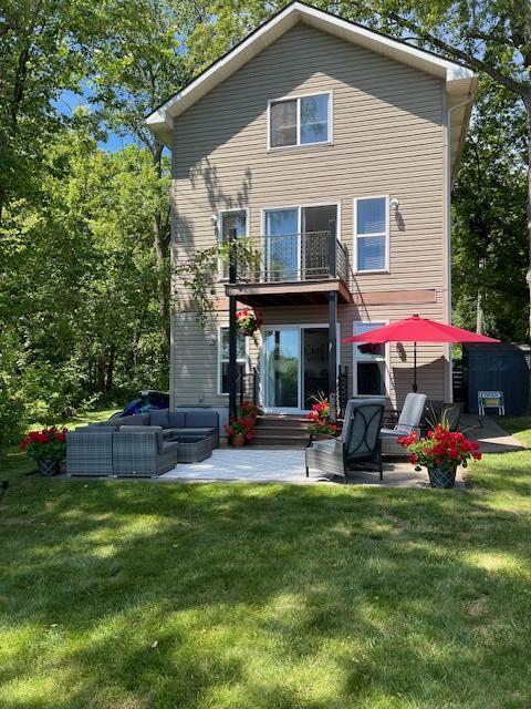 back of property with a yard, a balcony, and a patio