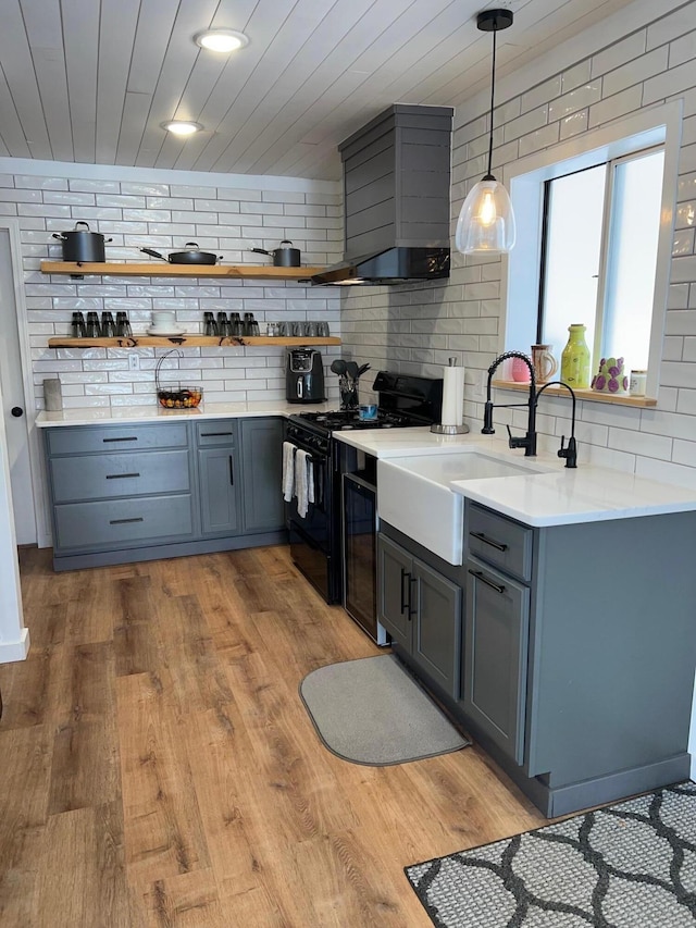 kitchen with decorative backsplash, wall chimney exhaust hood, wood-type flooring, electric range, and decorative light fixtures