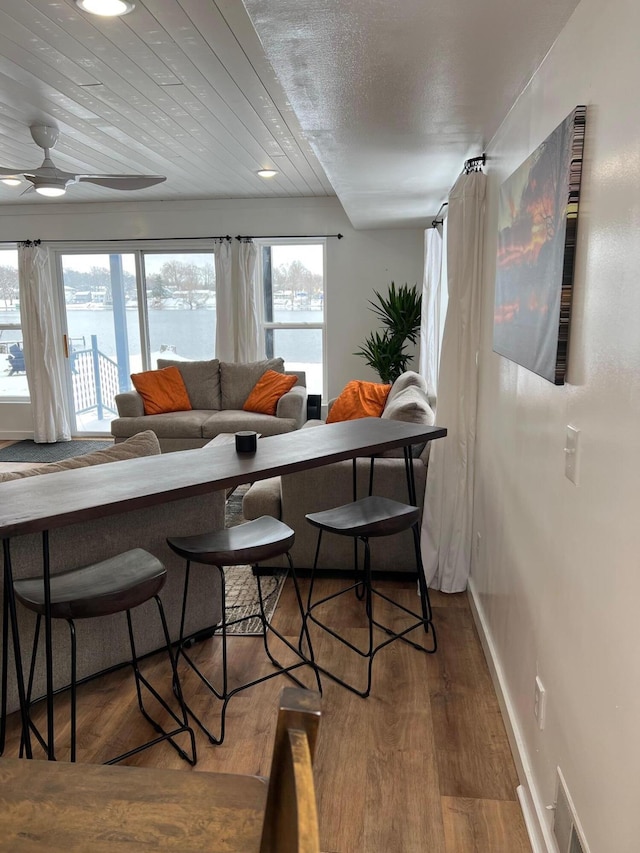 living room with ceiling fan, hardwood / wood-style floors, a water view, and wood ceiling