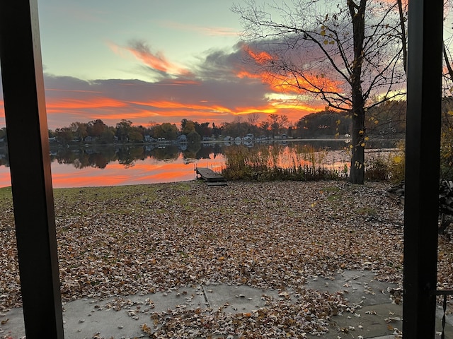 yard at dusk featuring a water view and a dock