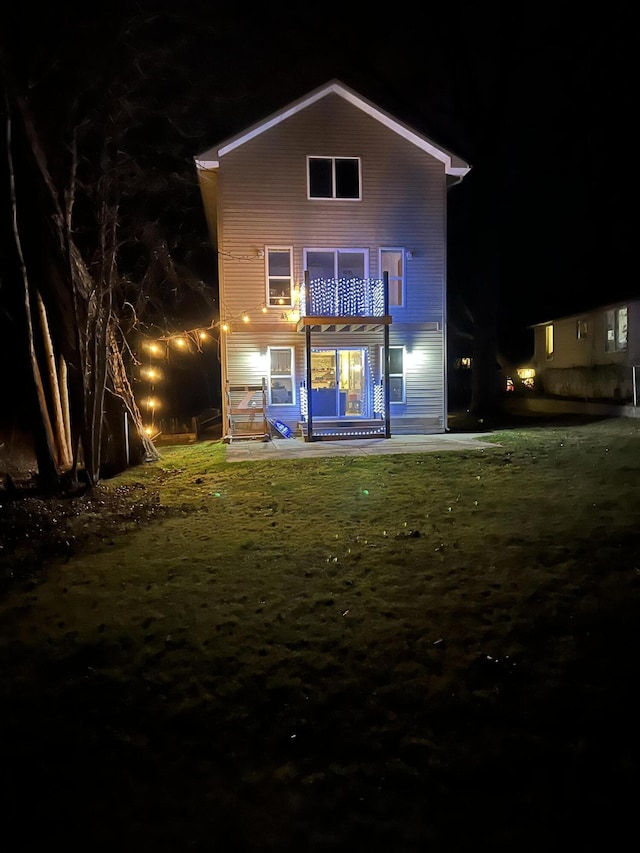 back house at night with a balcony and a lawn