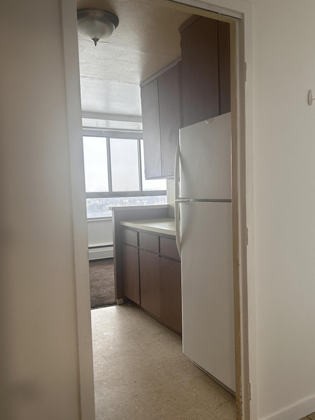 kitchen with a textured ceiling, white fridge, and baseboard heating