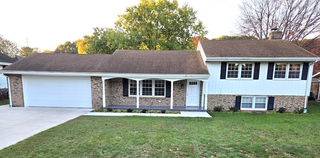 tri-level home featuring a garage, covered porch, and a front lawn