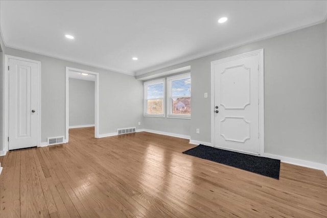 foyer entrance with ornamental molding and light hardwood / wood-style flooring