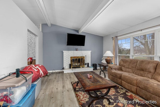 living room featuring a fireplace, vaulted ceiling with beams, and light wood-type flooring