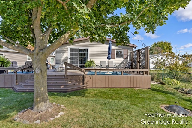 rear view of property featuring a yard and a deck