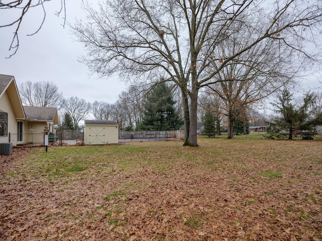 view of yard featuring a shed, a fenced backyard, and an outbuilding