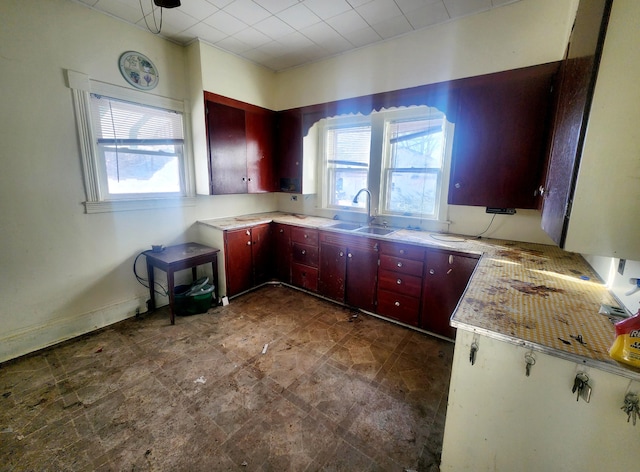 kitchen featuring dark brown cabinets, light countertops, baseboards, and a sink