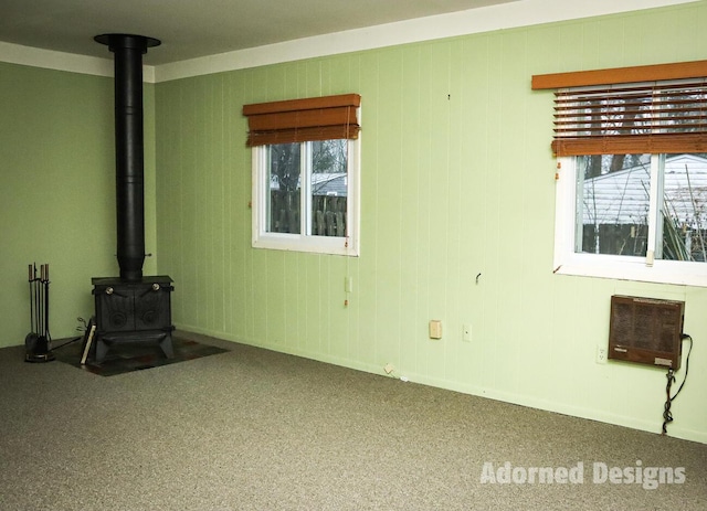 unfurnished living room with heating unit, carpet floors, and a wood stove