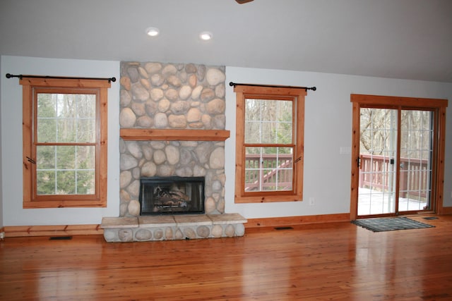 unfurnished living room featuring a healthy amount of sunlight, a fireplace, and hardwood / wood-style flooring