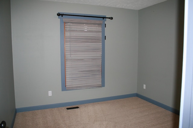 unfurnished room featuring a textured ceiling and carpet