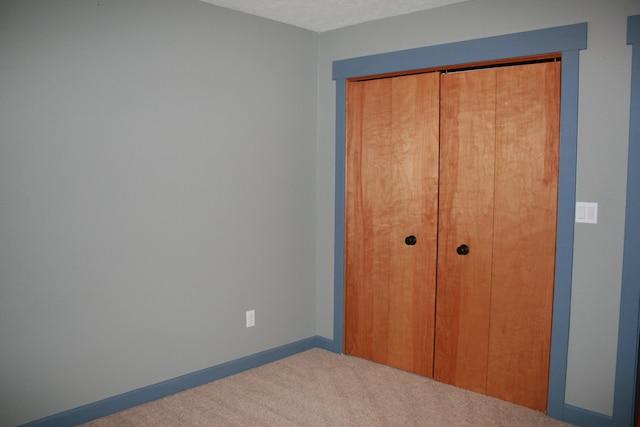 unfurnished bedroom with a closet and light carpet