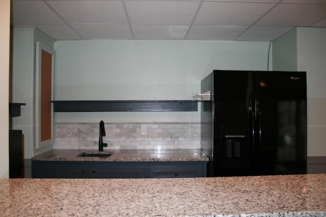 kitchen with sink, black fridge, a paneled ceiling, and tasteful backsplash