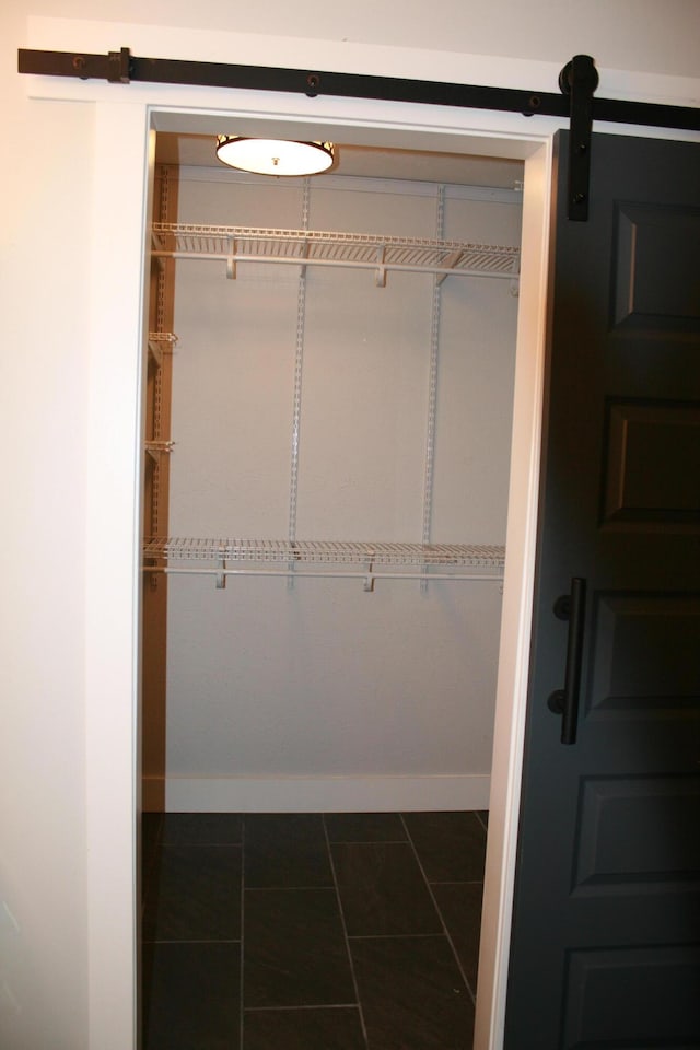 spacious closet featuring dark tile patterned flooring and a barn door