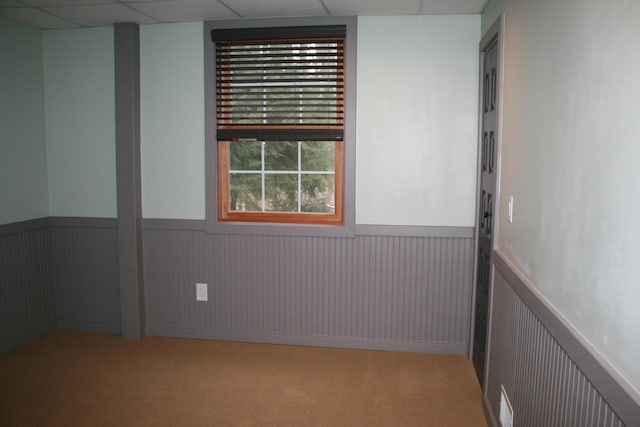 carpeted spare room with a paneled ceiling