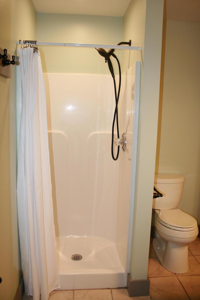 bathroom with curtained shower, toilet, and tile patterned floors