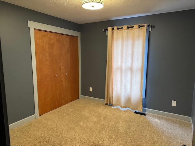 unfurnished bedroom featuring a closet, a textured ceiling, and carpet floors