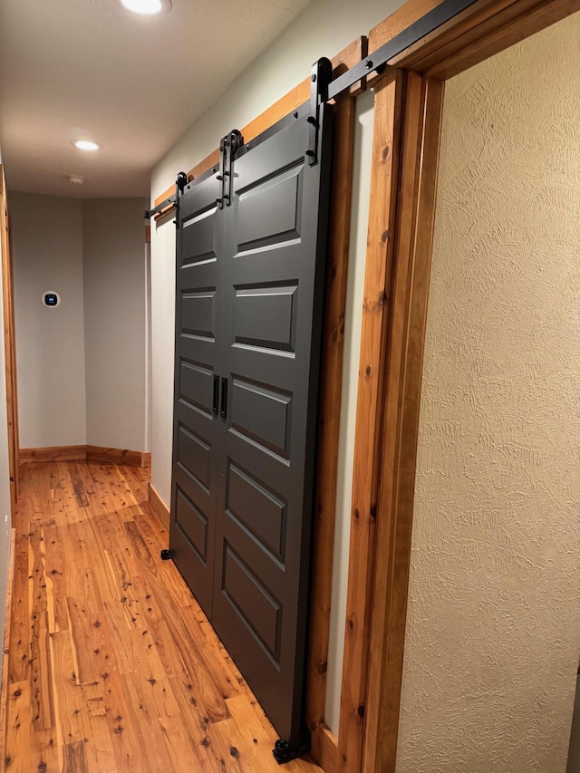 hall featuring light hardwood / wood-style floors and a barn door