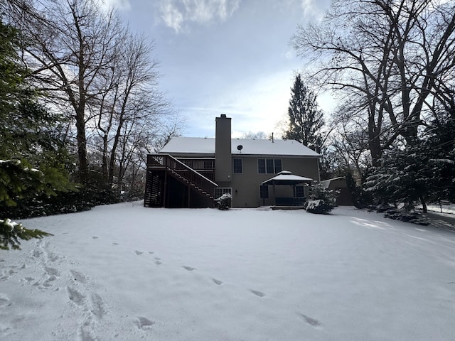 snow covered rear of property with a deck and a gazebo