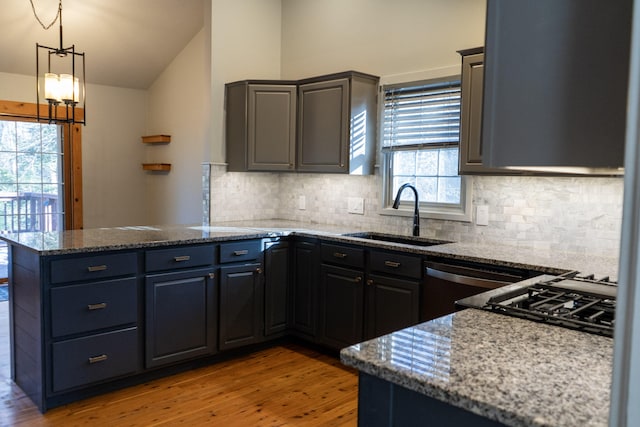 kitchen featuring stone countertops, vaulted ceiling, sink, and light hardwood / wood-style flooring