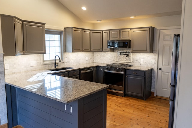 kitchen with lofted ceiling, sink, light stone countertops, black appliances, and kitchen peninsula