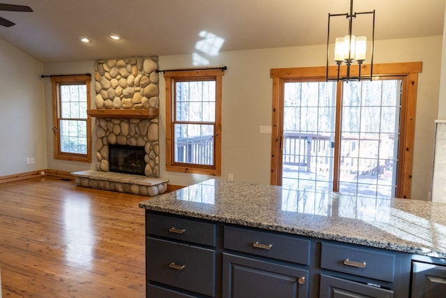 kitchen with wood-type flooring, decorative light fixtures, a fireplace, and a wealth of natural light