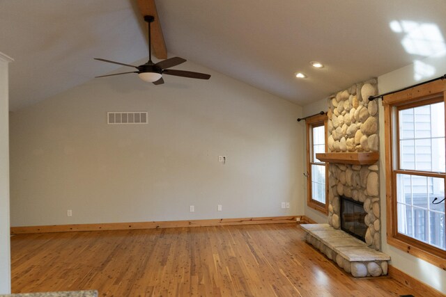 unfurnished living room featuring ceiling fan, vaulted ceiling with beams, a fireplace, and light hardwood / wood-style floors