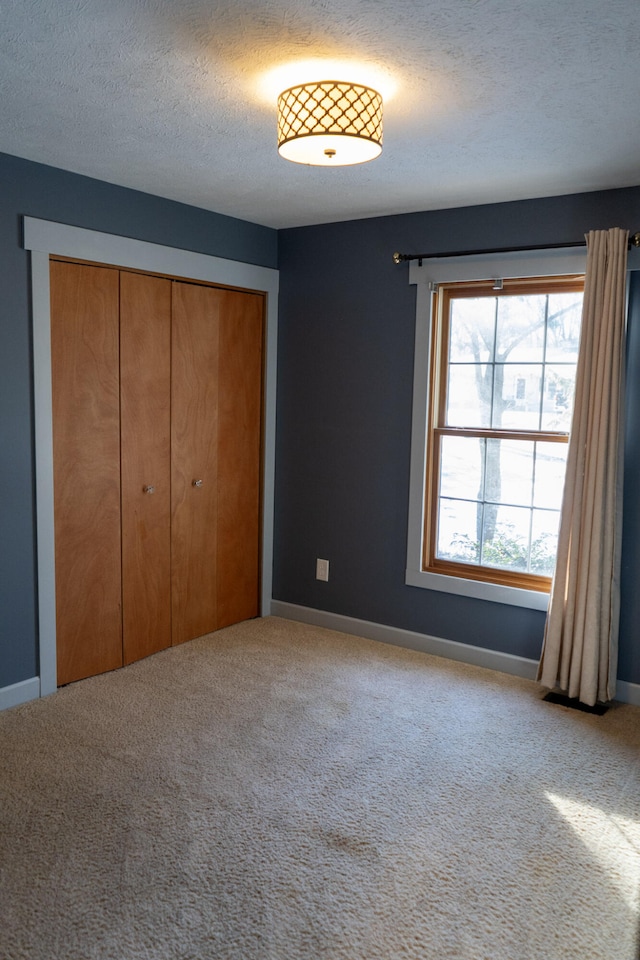 unfurnished bedroom with a closet, carpet floors, and a textured ceiling