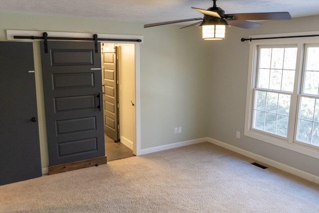 interior space featuring a barn door and ceiling fan