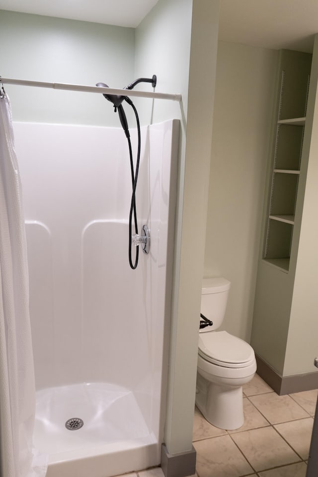 bathroom featuring tile patterned floors, toilet, and walk in shower