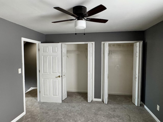 unfurnished bedroom with light carpet, ceiling fan, and multiple closets