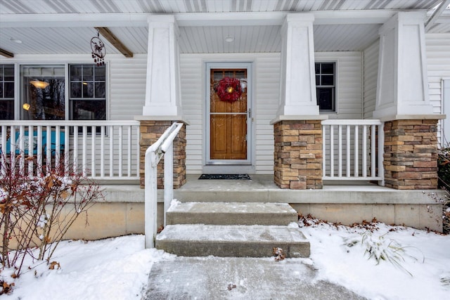 snow covered property entrance with covered porch